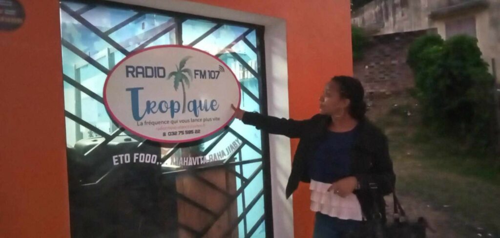 Une femme désignant le logo Radio Tropique